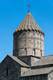 Detailed church tower with cross on top against a clear sky, main church Surb Pogos-Petros, Tatev