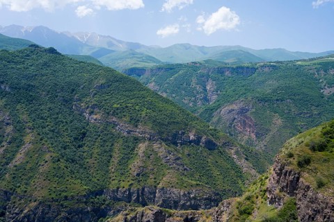 Green mountains with scattered clouds in the sky, peaceful and natural surroundings, view from