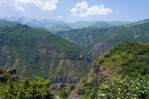 Green mountains under clear sky with white clouds, idyllic and peaceful atmosphere, view from the
