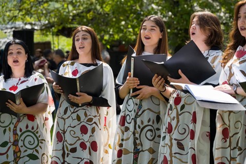 Women sing in a choir, elegantly dressed in painted robes, cheerful atmosphere, choir at Tatev