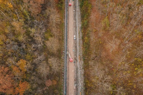 Aerial view of construction work along a slope in an autumn forest area, construction of the