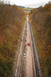 View of a construction site in a wooded autumn landscape with construction equipment and excavation