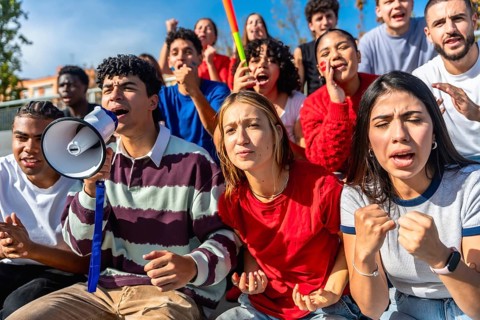 Diverse group of young people gathered for a protest or rally, expressing strong emotions and