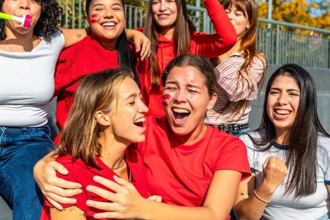 Group of excited diverse young women fans cheering loudly and celebrating a sports victory or game
