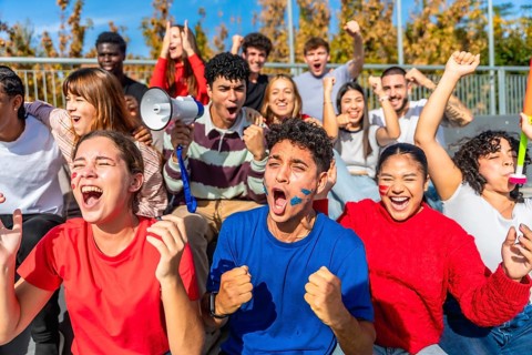 Energetic group of diverse young adults and friends showing excitement and support for their team,