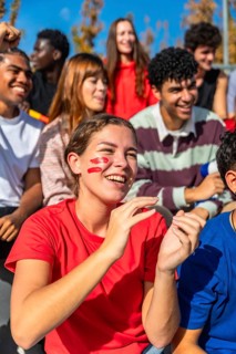 Young diverse friends and enthusiastic sports fans are cheering and clapping, showing excitement
