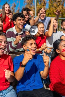 Young diverse fans intensely watching a sports game, cheering and celebrating together with face