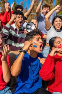 Young diverse people in a stadium are intensely cheering and shouting, supporting their team while
