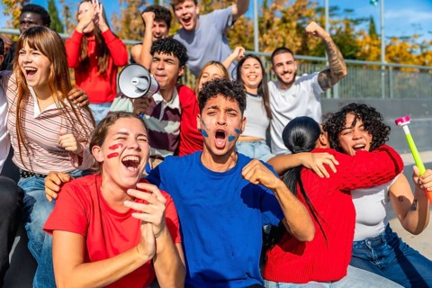 Group of diverse young sports fans celebrating and cheering loudly, showing strong emotion with