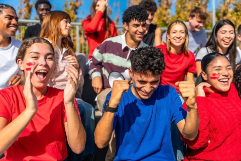 Energetic, diverse group of young adult spectators passionately cheering and celebrating their