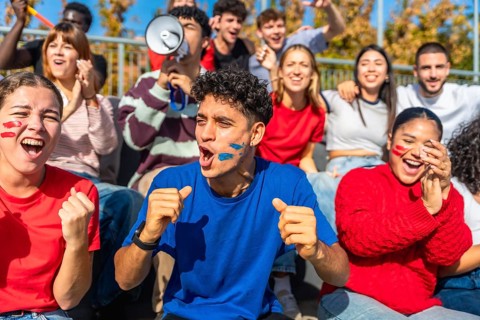Multiracial young people celebrating and cheering passionately in a stadium, showing excitement and