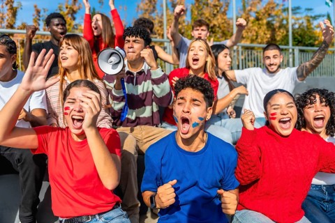 Enthusiastic young fans of diverse ethnicities and genders celebrating and cheering loudly,