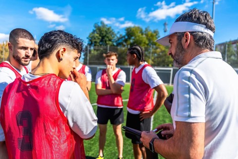 Soccer coach providing instructions and discussing game strategy with a group of young male team