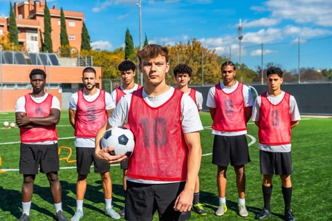 Coach, players and athletes preparing for soccer training, practicing on a green turf field during