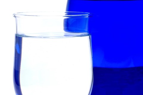 Glass with mineral water, small carbonated pearls on the edge of the glass, drinking water
