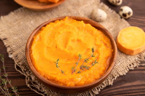 Sweet potato porridge in wooden bowl on wooden background and linen textile. Diet, healthy eating