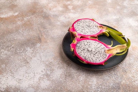 Ripe Pitaya on blue plate on brown concrete background, side view, copy space, minimalism