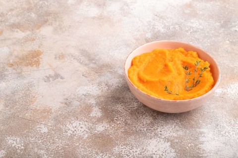 Sweet potato porridge in ceramic bowl on brown concrete background. Diet, healthy eating concept.