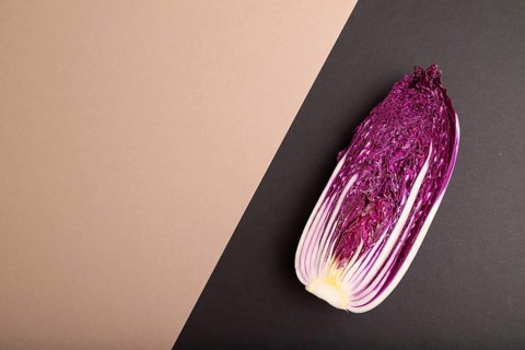 Purple Chinese cabbage on brown and black pastel paper background, top view, flat lay, copy space,
