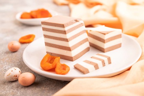 Cocoa and milk jelly with dried apricots on brown concrete background and orange textile, side