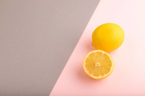Yellow Lemon Cut in half on gray and pink pastel paper background. Side view, copy space. healthy