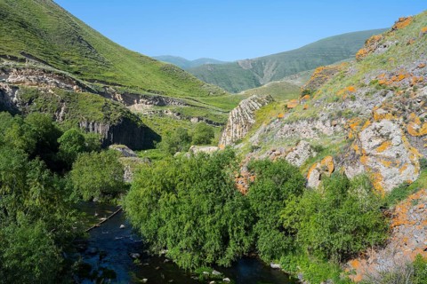 A lush valley crossed by a river, surrounded by tall green mountains under a clear sky, Vorotan