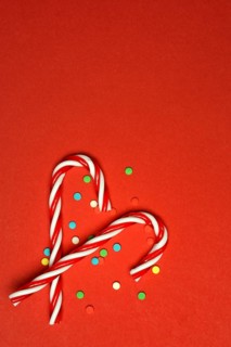 Candy canes and sugar confetti against red background, Christmas