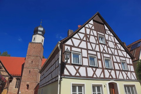 Half-timbered house and tower of the Catholic Church, town of Heideck in the district of Roth,