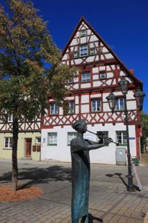 Half-timbered houses and fountain figure flute player, on Rathausplatz, city of Heideck in the