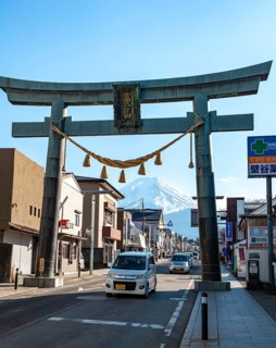 Large torii gate on above a street, street scene, in the back volcano Mt. Fuji, Fujiyoshida,