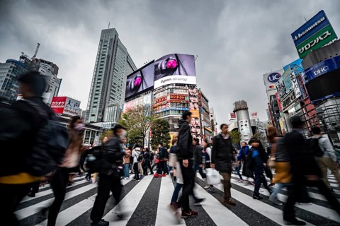 Crowd crossing zebra crossing on a large intersection, motion blur, back modern houses with