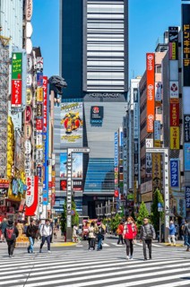 Bustling street scene in Japan with modern buildings and colorful billboards, figure of Godzilla