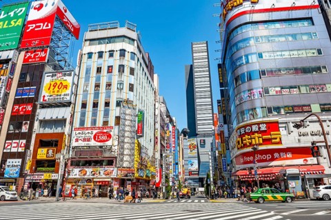 Bustling street scene in Japan with modern buildings and colorful billboards, figure of Godzilla