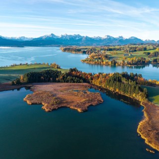 Large lake in autumn surroundings with the Alps in the distance under clear skies, Illasbergsee,