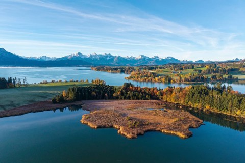 View of a lake with autumn leaves and mountains in the background under a clear sky, Illasbergsee,