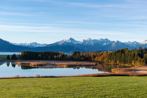 View of a lake surrounded by forests and snow-covered mountains in an autumnal atmosphere,