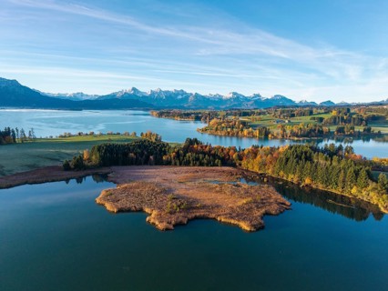 Clear image of a lake surrounded by autumn trees and mountain views, Illasbergsee, Forggensee, near