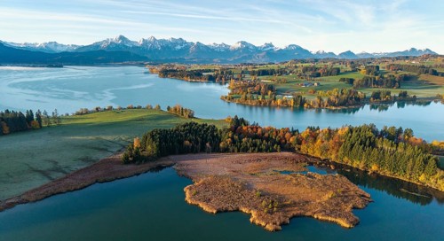 Autumn scene with a lake surrounded by green landscape and mountains, Illasbergsee, Forggensee,