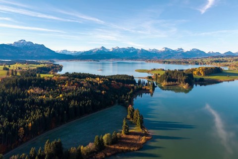 Autumn mountain landscape with a quiet lake and forests under blue sky, Illasbergsee, Forggensee,
