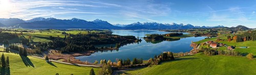 Panoramic view of a green landscape with lake and mountains under a clear sky, Illasbergsee,
