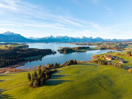 Panoramic view of meadows, a lake and mountain peaks in the distance, Illasbergsee, Forggensee,