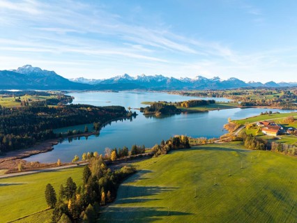 Rural scene with vast meadows and a lake, framed by mountains, Illasbergsee, Forggensee, near