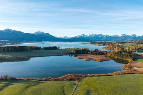 Wide landscape with lake surrounded by mountains and autumn trees under clear skies, Illasbergsee,