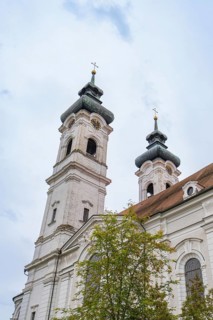 Two tall baroque church towers with crosses in the background of a cloudy sky, ZFP Zwiefalten,