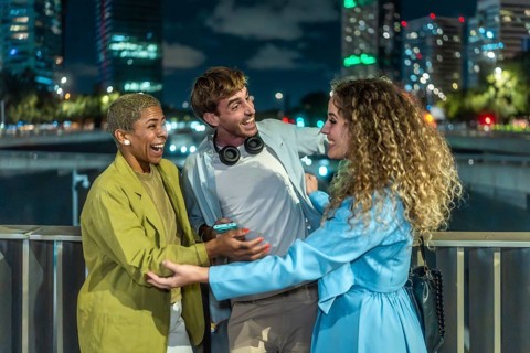 Diverse young adults laughing and bonding on a city bridge at night, candidly enjoying each other's