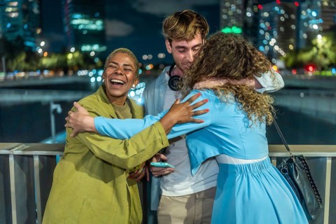 Diverse group of young adult friends expressing happiness and embracing each other, showing