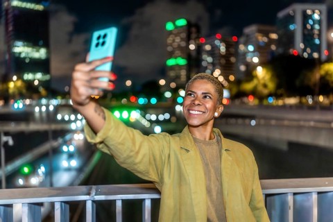 Woman with short blonde hair and happy expression capturing a selfie with her smartphone against a