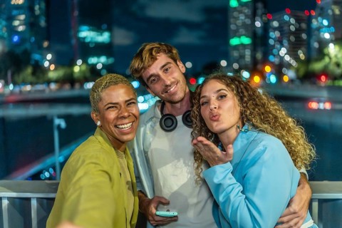 Diverse group of young adult friends enjoying a fun night out in the city, smiling and posing for a