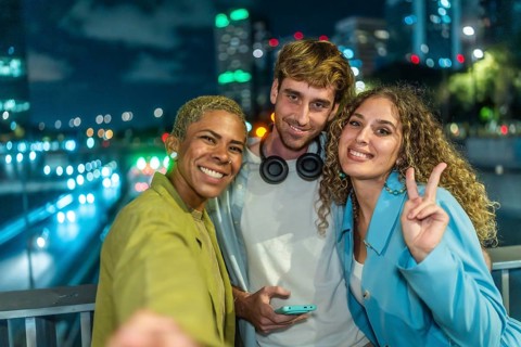 Group of diverse friends smiling and posing for a selfie at night, celebrating friendship and youth
