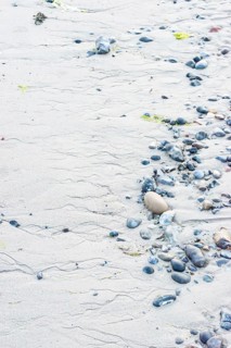 Pattern in sand with scattered stones on a quiet sandy beach, drainage channels, runoff water,